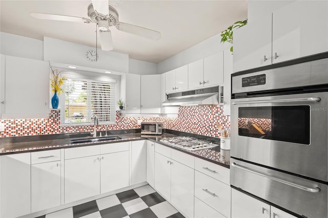 kitchen featuring under cabinet range hood, stainless steel appliances, a sink, tile patterned floors, and a warming drawer