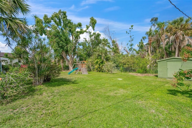 view of yard featuring an outbuilding, a playground, fence, and a shed