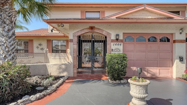 view of exterior entry with a garage, aphalt driveway, and stucco siding