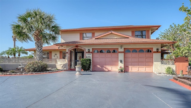 view of front of property with driveway, a garage, and fence