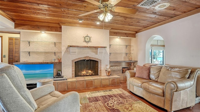 living area with a tile fireplace, wood ceiling, crown molding, and arched walkways