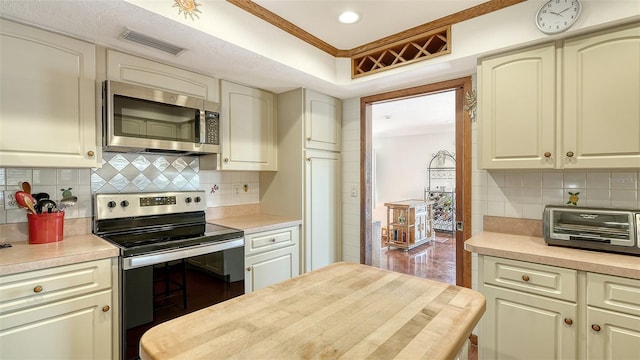 kitchen featuring stainless steel appliances, light countertops, visible vents, and crown molding