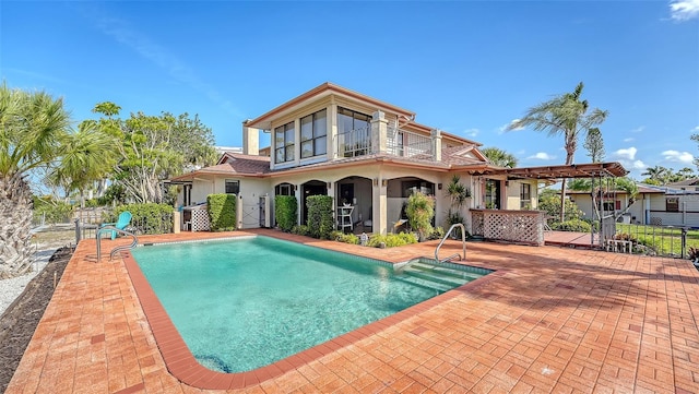 rear view of house with a fenced in pool, fence, and a balcony