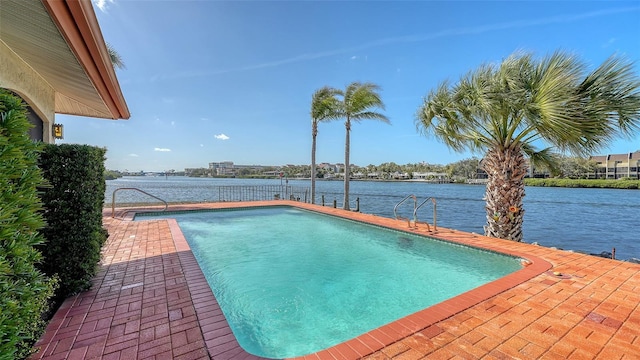 outdoor pool with a water view and a patio