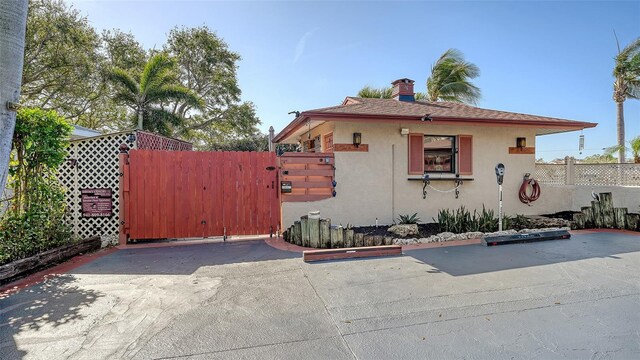 view of front of home with a shingled roof, a gate, fence, and stucco siding