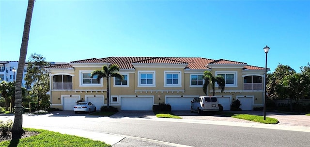 view of front of property with a garage, a tile roof, and stucco siding