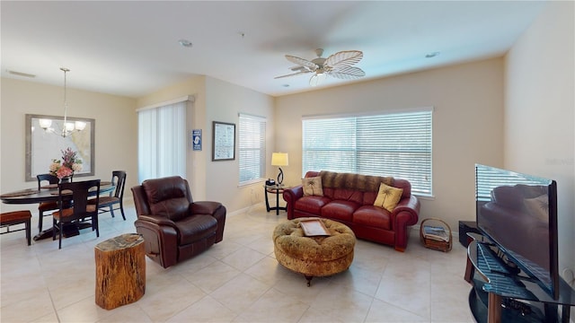 living area with light tile patterned floors, ceiling fan with notable chandelier, visible vents, and baseboards