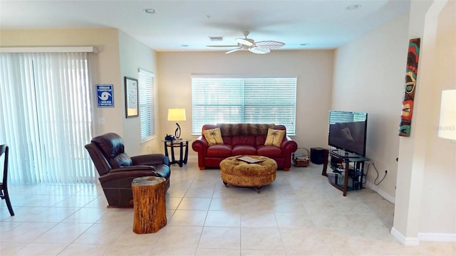 living area featuring light tile patterned flooring, a ceiling fan, and baseboards