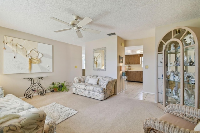 living area featuring a textured ceiling, visible vents, carpet flooring, and tile patterned floors