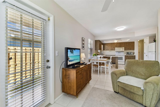 living area with light tile patterned floors, a ceiling fan, and baseboards