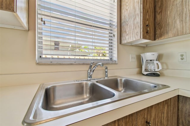 kitchen with brown cabinetry, light countertops, and a sink