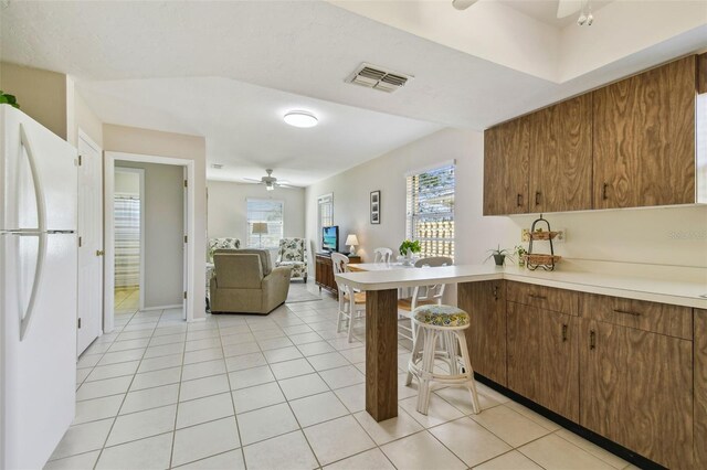 kitchen featuring plenty of natural light, freestanding refrigerator, visible vents, and ceiling fan