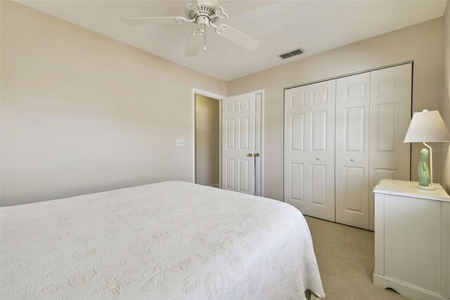 bedroom with light colored carpet, a closet, visible vents, and ceiling fan