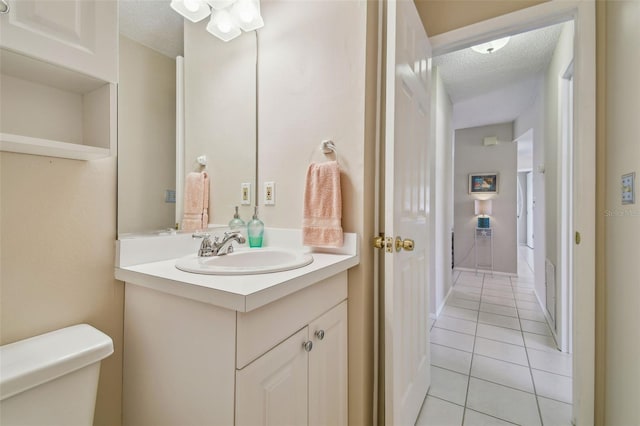 full bathroom with a textured ceiling, tile patterned flooring, vanity, and toilet