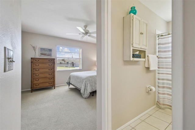 bedroom with light carpet, ceiling fan, light tile patterned flooring, and baseboards