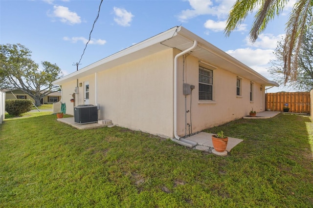 view of side of property featuring central AC unit, a lawn, fence, and stucco siding