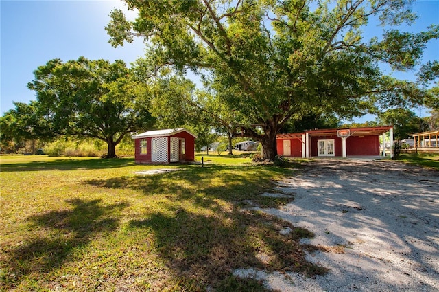 view of yard with driveway, french doors, and an outdoor structure