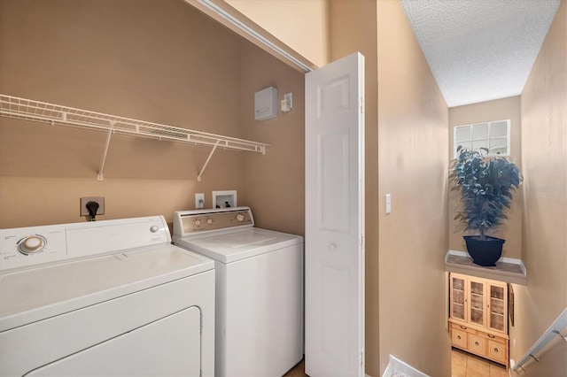 washroom with a textured ceiling, laundry area, and washing machine and clothes dryer