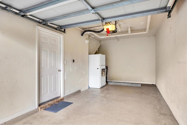 garage featuring a garage door opener, freestanding refrigerator, and baseboards