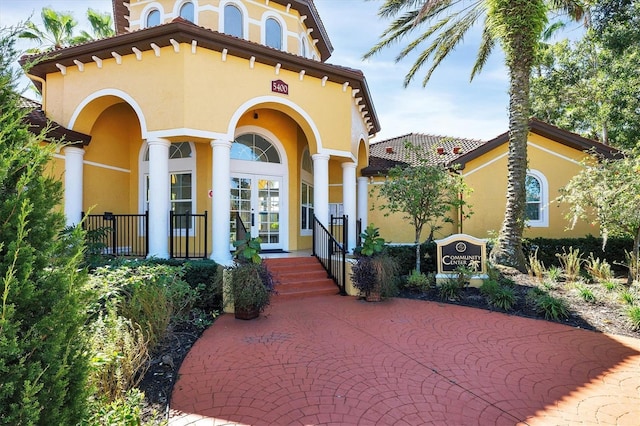 view of front of house featuring stucco siding, french doors, and a tile roof