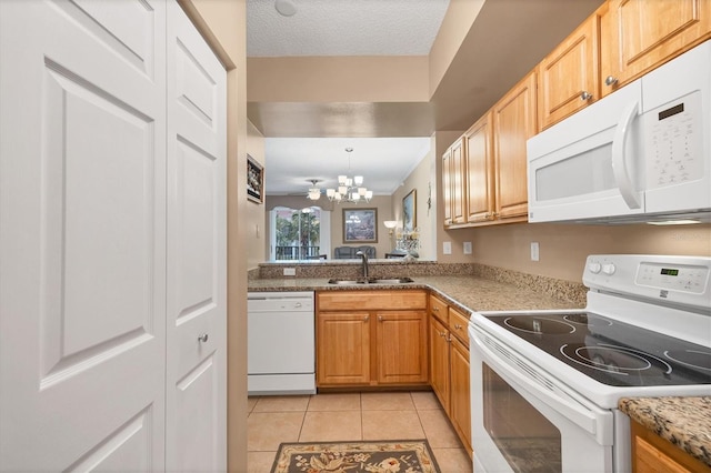 kitchen with white appliances, light tile patterned floors, a sink, a textured ceiling, and a chandelier