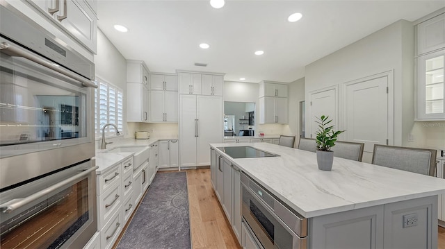 kitchen featuring a center island, recessed lighting, light wood-style flooring, stainless steel appliances, and a sink