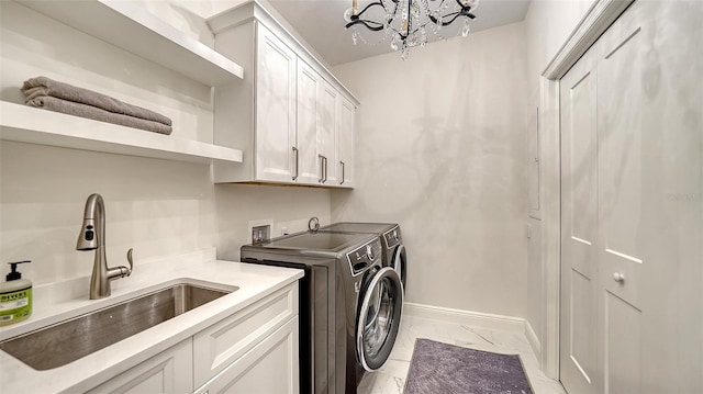 laundry area featuring marble finish floor, a sink, washing machine and dryer, cabinet space, and baseboards