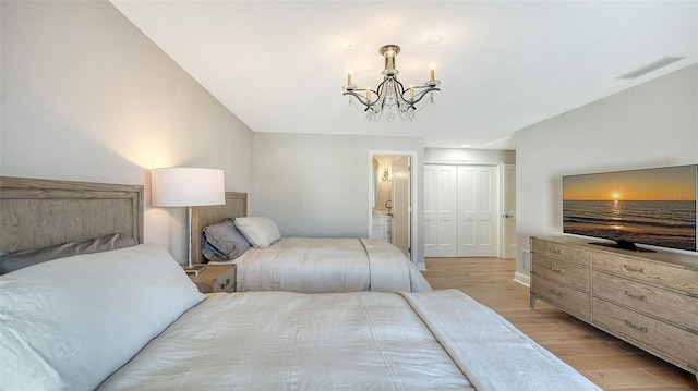 bedroom featuring visible vents, light wood-style flooring, connected bathroom, a closet, and a chandelier