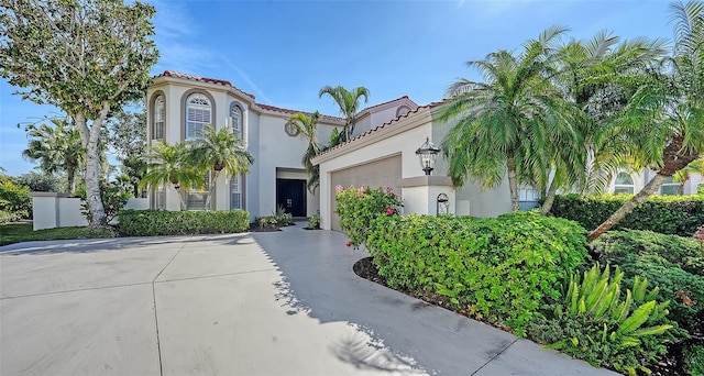 mediterranean / spanish-style house with a tiled roof, a garage, driveway, and stucco siding