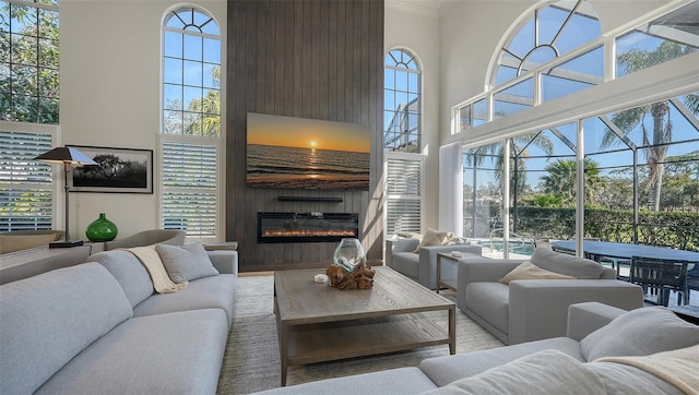 living room featuring a wealth of natural light, a fireplace, crown molding, and a high ceiling