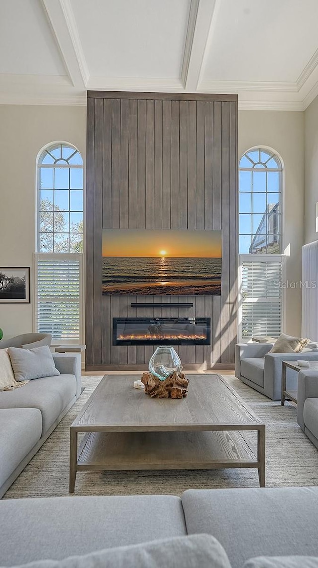 living room featuring crown molding, beamed ceiling, and a large fireplace