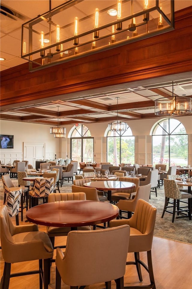 dining area with beamed ceiling, a notable chandelier, and wood finished floors