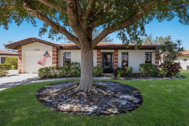 view of front of home with a garage, a front yard, driveway, and stucco siding