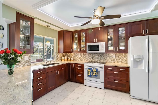 kitchen with a sink, decorative light fixtures, white appliances, and tasteful backsplash