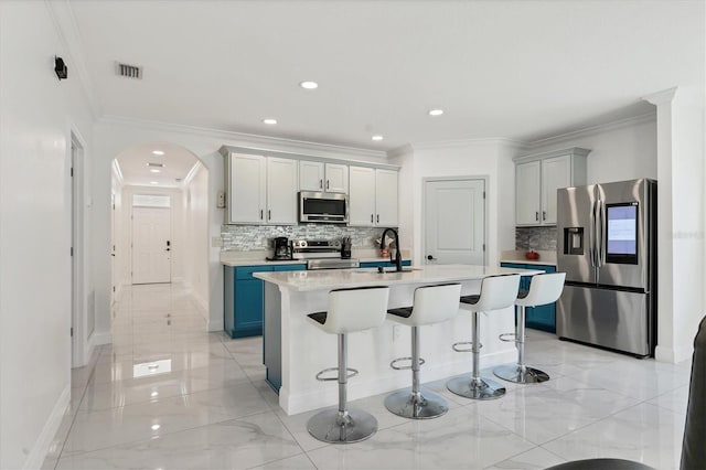 kitchen with a breakfast bar, light countertops, appliances with stainless steel finishes, arched walkways, and a sink