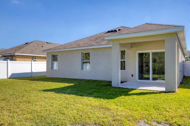 rear view of property featuring a patio, a yard, fence, and stucco siding