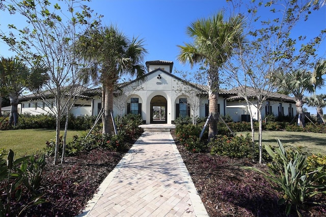 mediterranean / spanish-style house with stucco siding, a tiled roof, and a front yard