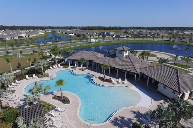 community pool with fence, a patio area, a residential view, and a water view