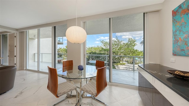 dining room featuring a healthy amount of sunlight, marble finish floor, and expansive windows