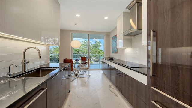 kitchen featuring marble finish floor, wall chimney range hood, modern cabinets, and a sink