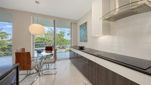 kitchen featuring dark countertops, modern cabinets, marble finish floor, black electric cooktop, and exhaust hood