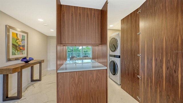 laundry area featuring stacked washer and dryer, recessed lighting, marble finish floor, and laundry area