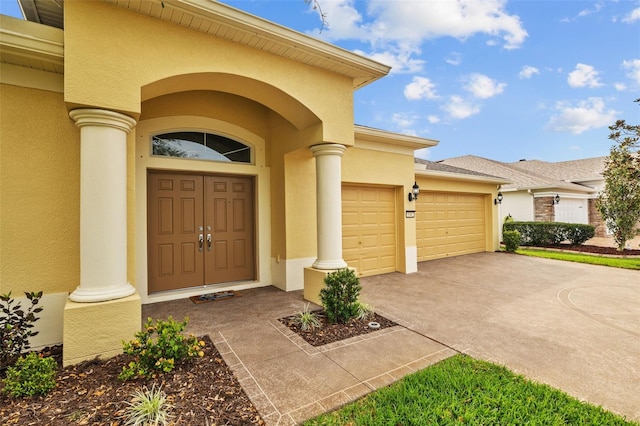 property entrance featuring stucco siding, concrete driveway, and a garage