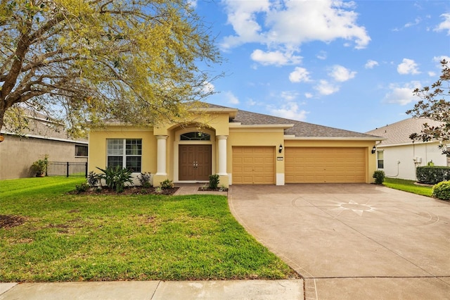 view of front of property with concrete driveway, an attached garage, fence, a front lawn, and stucco siding