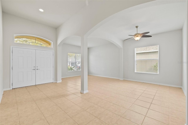 entrance foyer featuring arched walkways, light tile patterned flooring, and baseboards