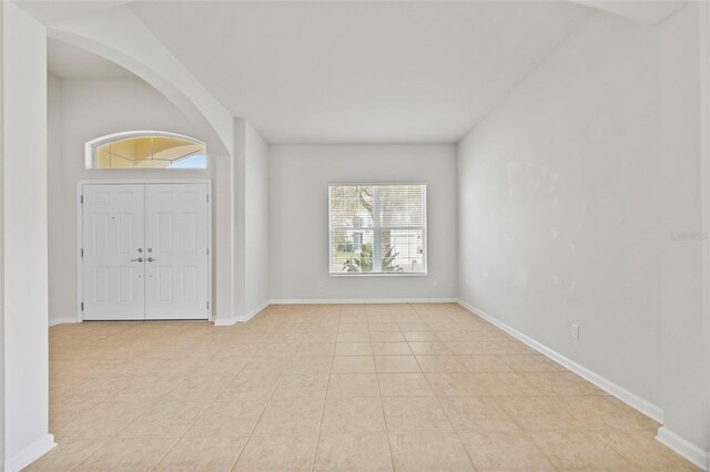 foyer featuring baseboards and arched walkways