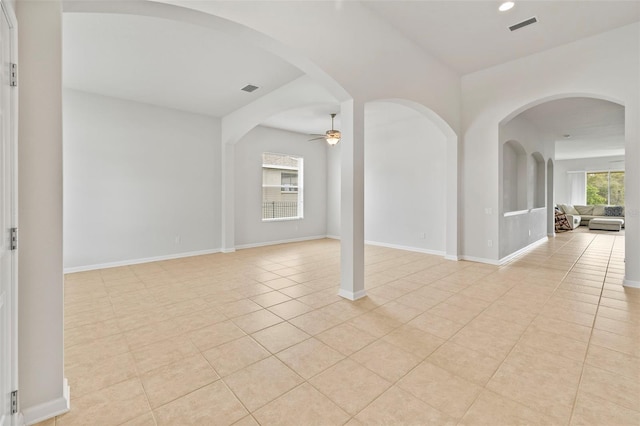 empty room with light tile patterned floors, ceiling fan, visible vents, and baseboards