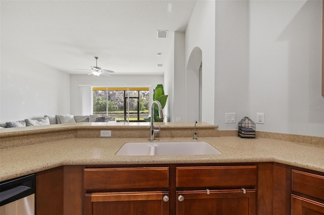 kitchen featuring light stone counters, stainless steel dishwasher, open floor plan, a sink, and ceiling fan