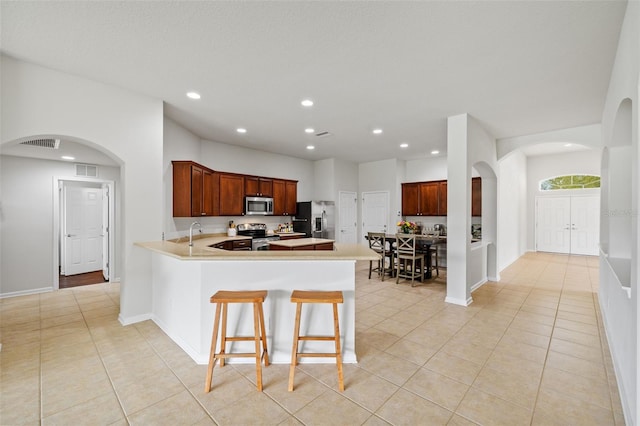 kitchen featuring a peninsula, light tile patterned floors, visible vents, and appliances with stainless steel finishes