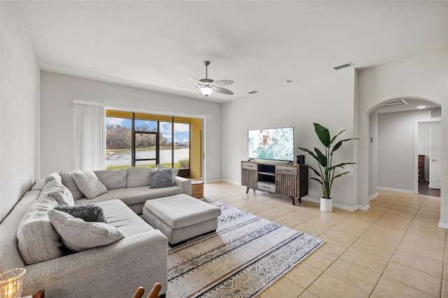 living room with arched walkways, visible vents, ceiling fan, and light tile patterned floors